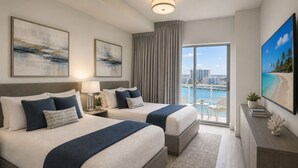 Ein Hotelzimmer mit zwei Betten, einem großen Fenster mit Blick auf die Stadt, einem Fernseher und einem Balkon mit einem Sessel.