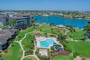Ein Resort mit einem Swimmingpool, umgeben von gepflegten Rasenflächen und Palmen, mit Blick auf ein Gewässer.