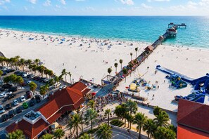 A beach with a pier, palm trees, and a parking lot. - Relaxed Stay Suite Lower Floor (Clearwater)