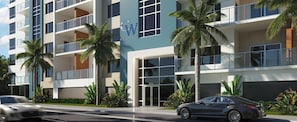 Un hôtel à plusieurs étages au design moderne, doté de balcons, de grandes fenêtres et d’un aménagement paysager de style tropical.