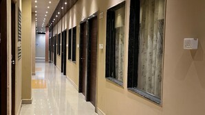A hotel corridor with a polished floor, wooden ceiling, and multiple doors with windows.