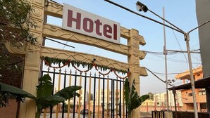 A hotel entrance with a sign, a gated entrance, and a paved pathway.