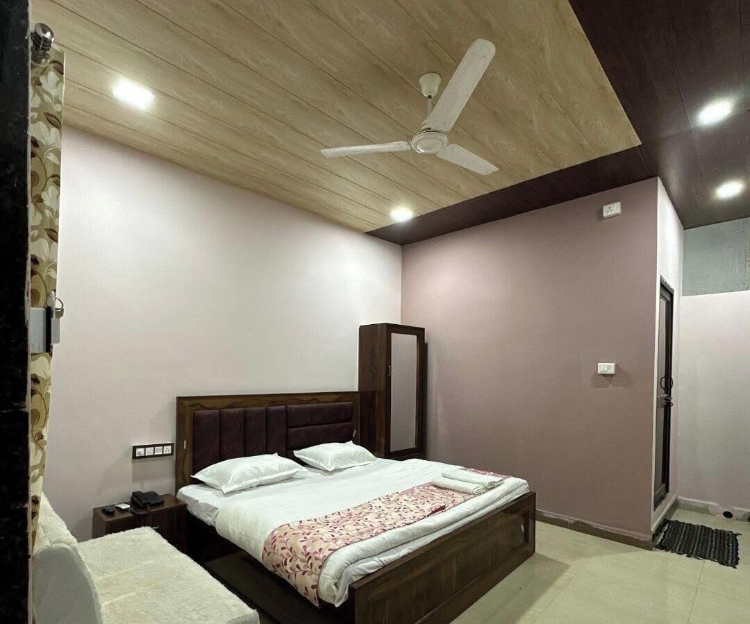 A bedroom with a bed, a nightstand, a mirror, a ceiling fan, and recessed lighting.