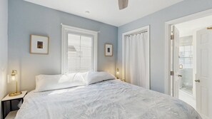 Ein Schlafzimmer mit einem Bett, zwei Nachttischen, einem Fenster und einer Tür.