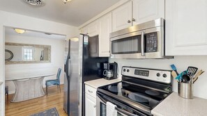 A modern kitchen with stainless steel appliances, a dining area with a table and chairs, and a large mirror. - Rehoboth Beach Gem - Porch and walk to beach (Rehoboth Beach)