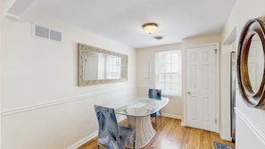 A dining room with a glass table, chairs, a large mirror, and a door. - Rehoboth Beach Gem - Porch and walk to beach (Rehoboth Beach)