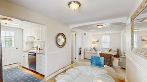 A spacious living area with a kitchen, a dining table, and a sofa. - Rehoboth Beach Gem - Porch and walk to beach (Rehoboth Beach)