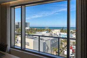 Una habitación con un ventanal grande que da a una vista panorámica de la ciudad, con edificios y una lejana vista al océano.