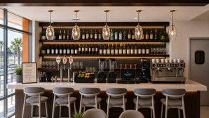 A bar area with multiple stools, a coffee machine, and a variety of liquor bottles. - Coastal Luxe Suite Upper Floor (Clearwater)