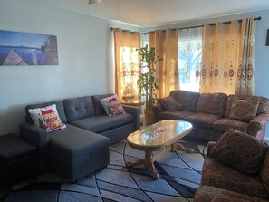 Un salon avec deux canapés, une table basse, une plante en pot et un tableau accroché au mur.