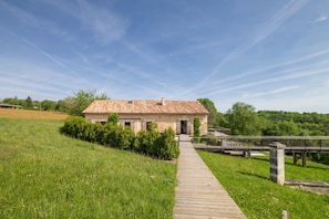 A rustic building with a tiled roof, a wooden pathway leading to it, and a grassy field in the background. - Fouleix Countryside Villa With Pool & Garden (Fouleix)