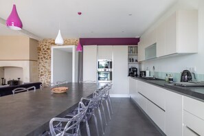 A modern kitchen with a central island, clear chairs, and a purple pendant light. - Fouleix Countryside Villa With Pool & Garden (Fouleix)