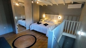 A bedroom with two beds, a wooden floor, a white railing, and a small rug. - LE DOMAINE DE L'HYLODE (Sainte-Anne)