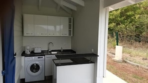 A compact kitchen with a washing machine, a coffee maker, and a sink. - LE DOMAINE DE L'HYLODE (Sainte-Anne)