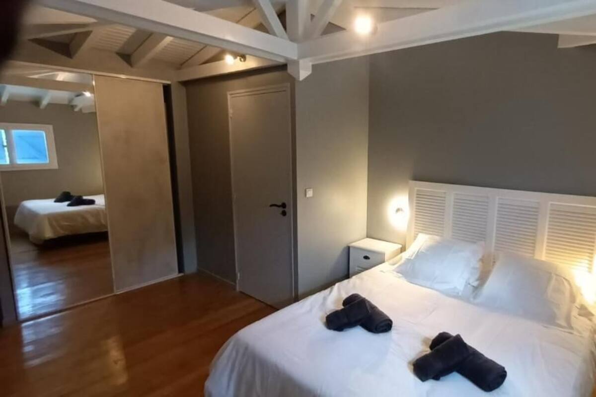 Un dormitorio con cama, mesitas de noche, un armario y un espejo.