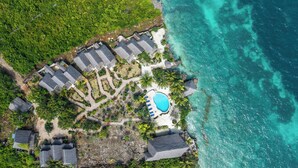 Vista aérea de un resort con varias edificaciones, una piscina y una costa.