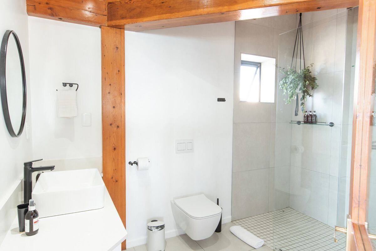 Un baño con lavamanos blanco, inodoro y zona de ducha.