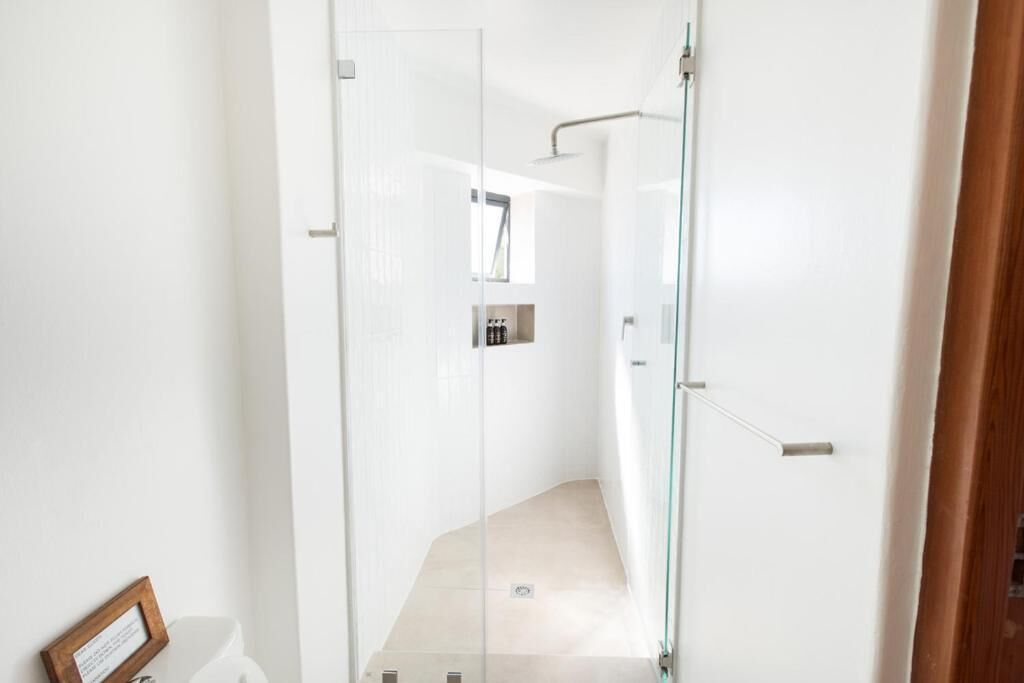 A modern bathroom with a glass shower enclosure, a visible toilet, and a framed picture on the wall.