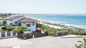 Una proprietà costiera con un edificio bianco, una recinzione in legno e vista sulla spiaggia.