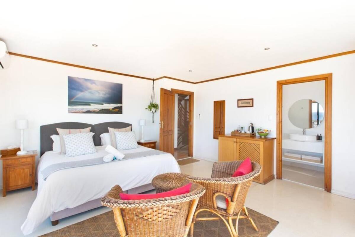 A bedroom with a bed, bedside tables, a dresser, a mirror, and a view of the outside.