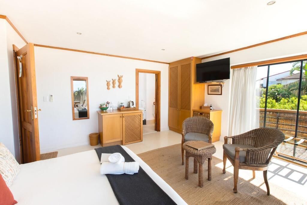 A hotel room with a bed, a desk, a chair, a TV, and a balcony with a view.