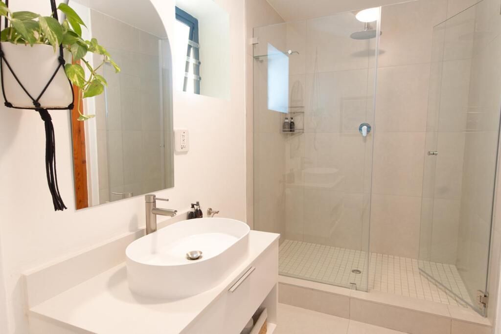 A modern bathroom with a white sink, a glass shower enclosure, and a mirror.