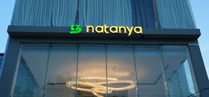 A building with a glass facade and the logo 'natanya' on the upper part. - HOTEL NATANYA (Thanjavur)