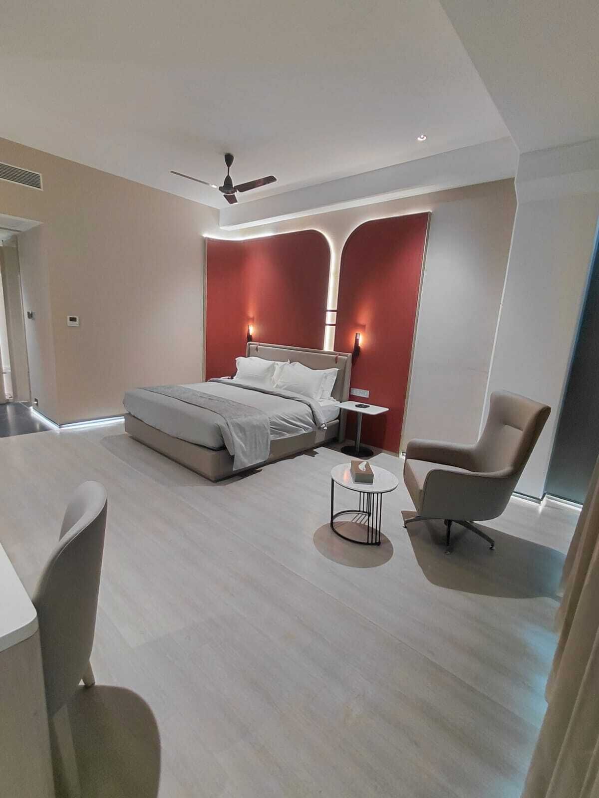 A modern bedroom with a bed, a chair, a small table, and a ceiling fan.