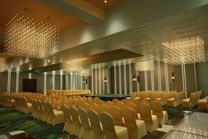 A conference room with rows of chairs, a long table, and modern lighting fixtures.
