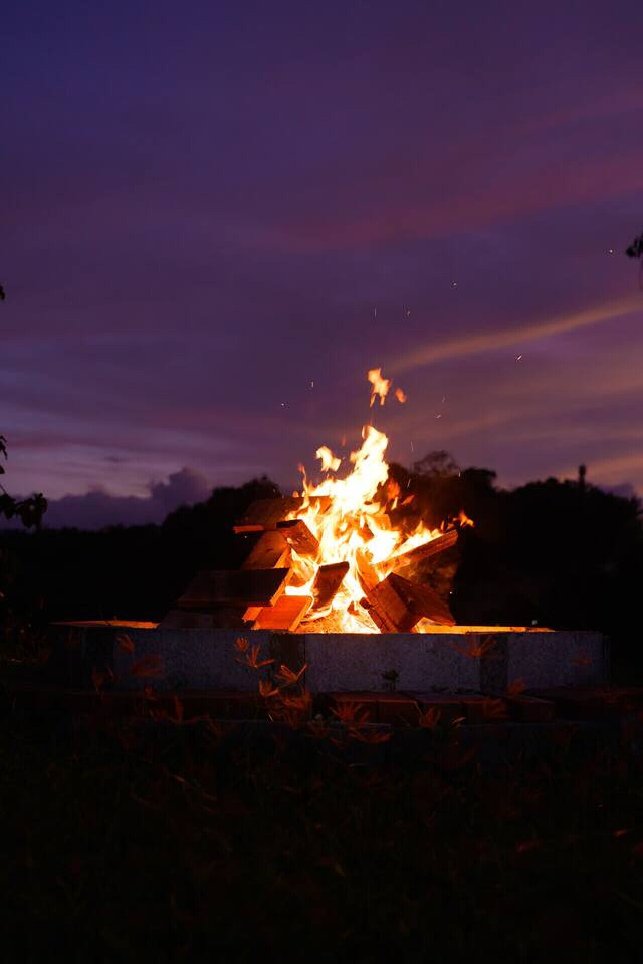 A campfire at night with a purple sky.