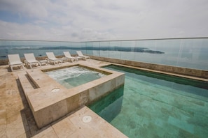 Ein Dachpool mit unendlicher Optik, klarem Wasser, einer Whirlwanne und Liegestühlen.