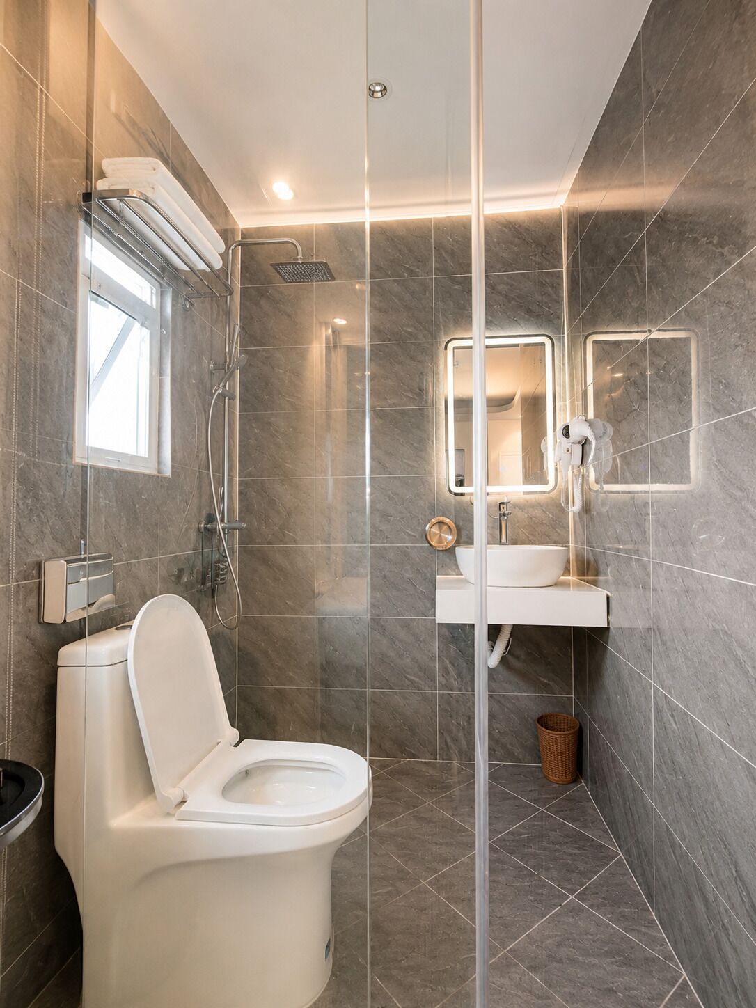 A modern bathroom with a toilet, shower, and a sink with a mirror.