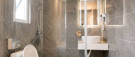 A modern bathroom with a toilet, shower, and a sink with a mirror.