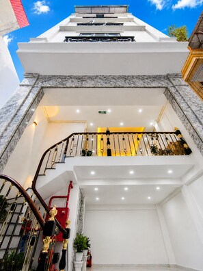Ein mehrstöckiges Hotelinterieur mit einer Treppe, Marmorböden und einem Balkon mit Geländer.