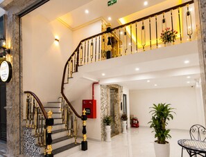 Eine imposante Treppe mit Geländer, Rauchmelder und Pflanzen in einer Hotelhalle.