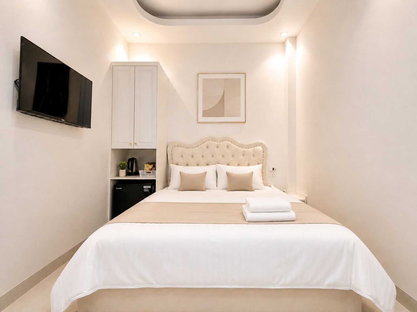 Un dormitorio ordenado con cama, televisión, armario y un cuadro en la pared.