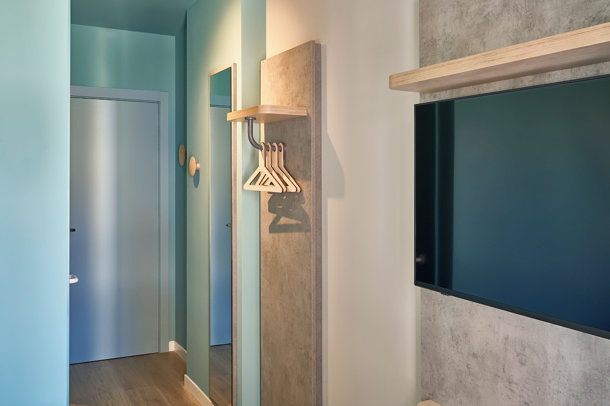 A hallway with a wooden coat rack, a door, and a wall-mounted television.