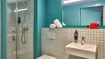 A bathroom with a glass shower enclosure, a white sink, and a mirror above it.