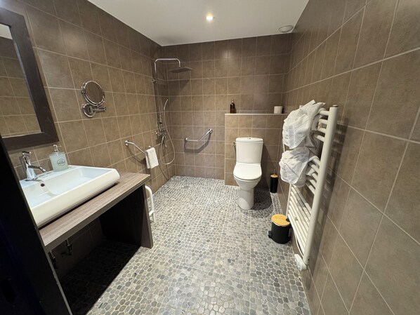 A modern bathroom with a sink, toilet, shower, and towel rack.