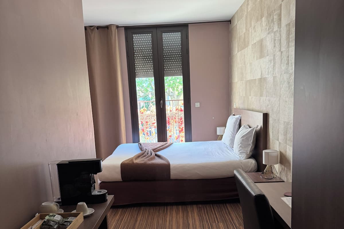Ein Hotelzimmer mit Bett, Schreibtisch, Stuhl und Blick ins Freie.