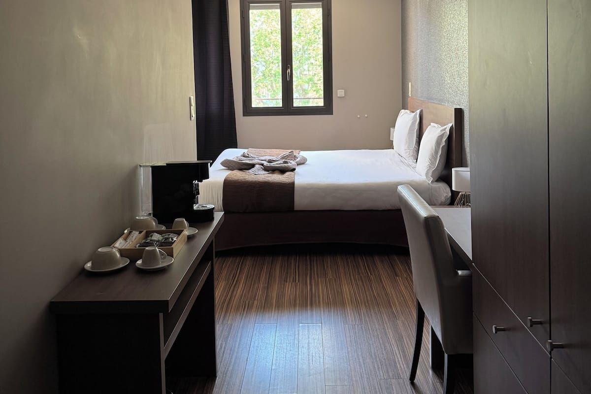 Ein Hotelzimmer mit Bett, Schreibtisch, Stuhl, Fernseher und Fenster.