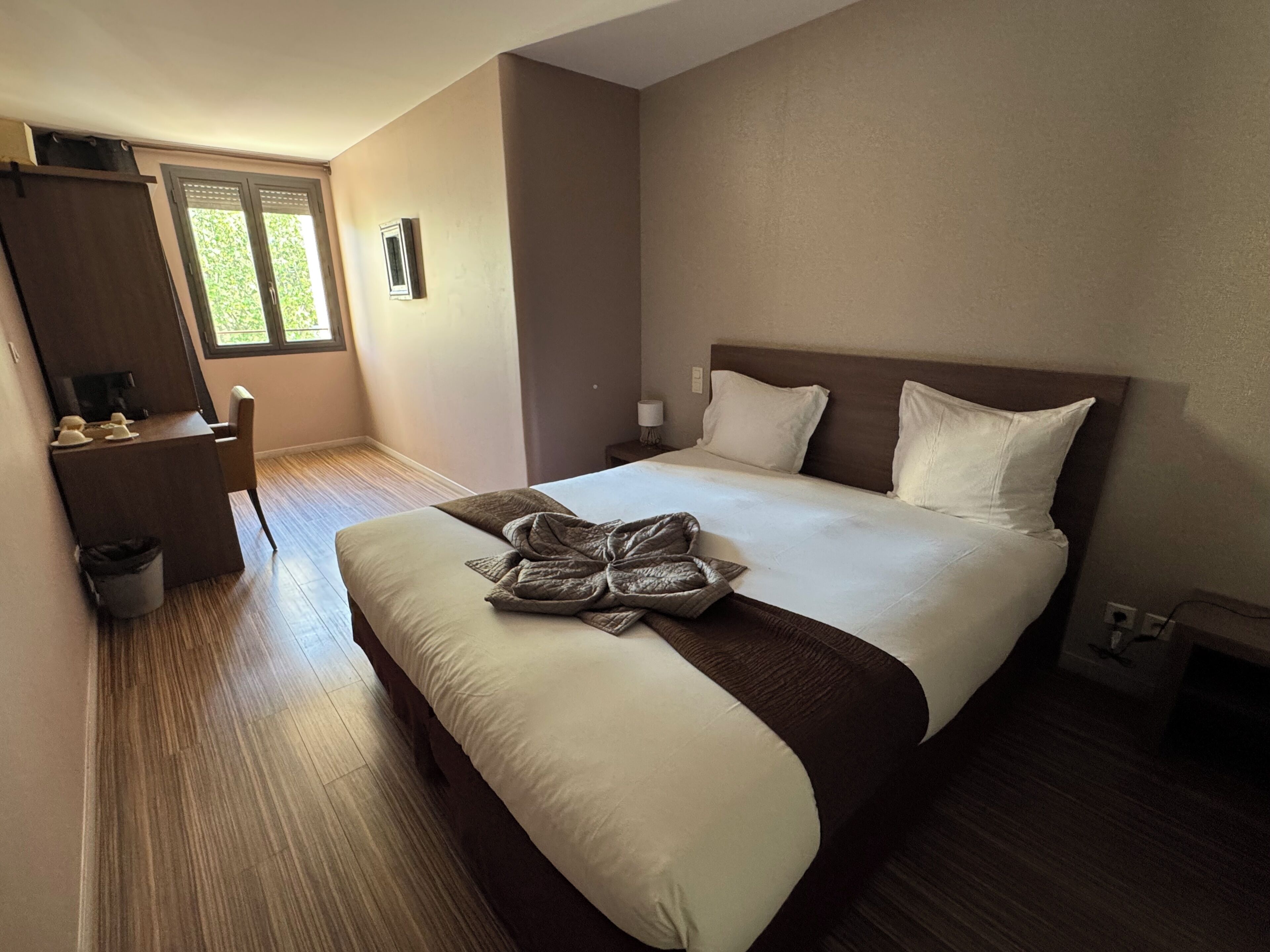 Una habitación de hotel con cama, escritorio, silla y ventana.