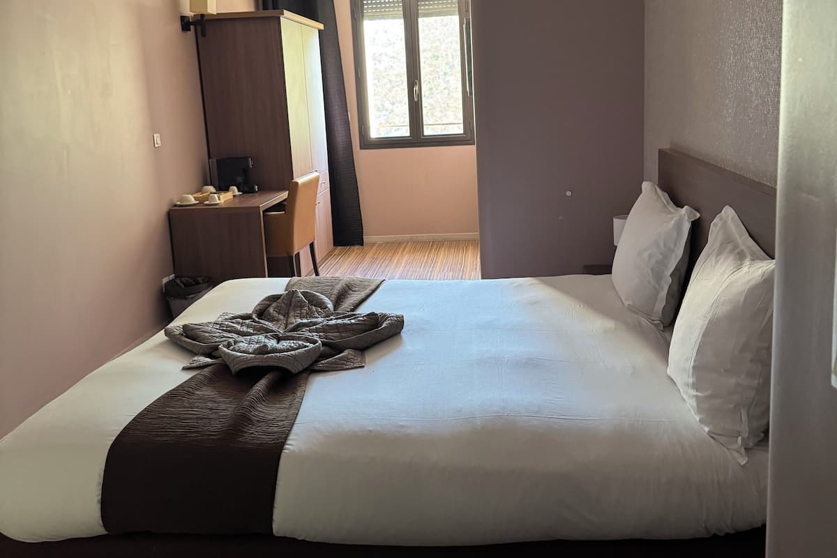 Ein Hotelzimmer mit einem großen Bett, einem Schreibtisch, einem Kleiderschrank und einem Fenster.