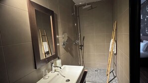 Ein modernes Badezimmer mit großem Spiegel, Waschbecken und Duschbereich.