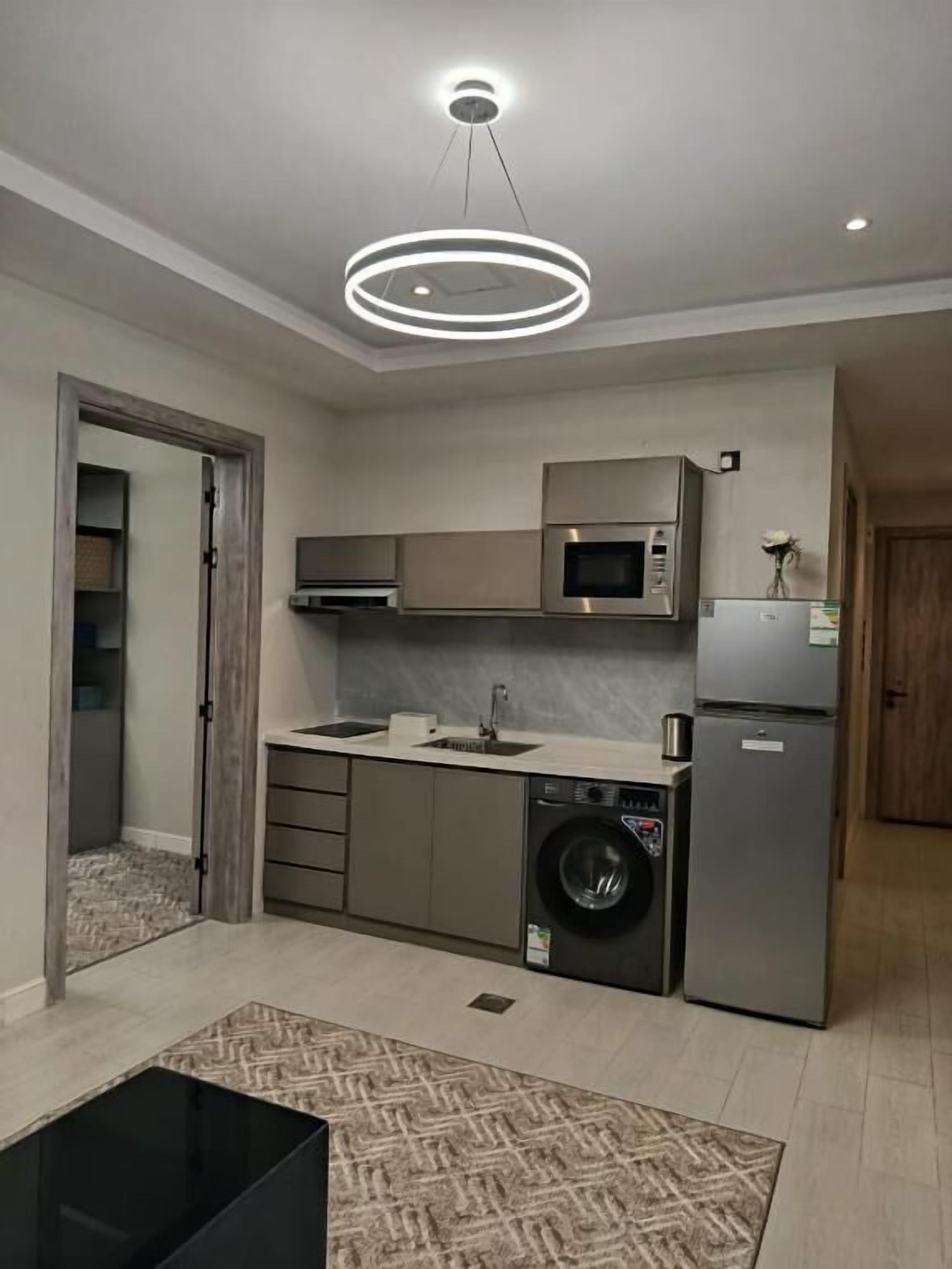 Una cocina moderna con electrodomésticos integrados, lavadora y comedor con mesa negra.