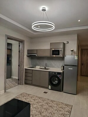 Een moderne keuken met inbouwapparatuur, een wasmachine en een eethoek met een zwarte tafel.