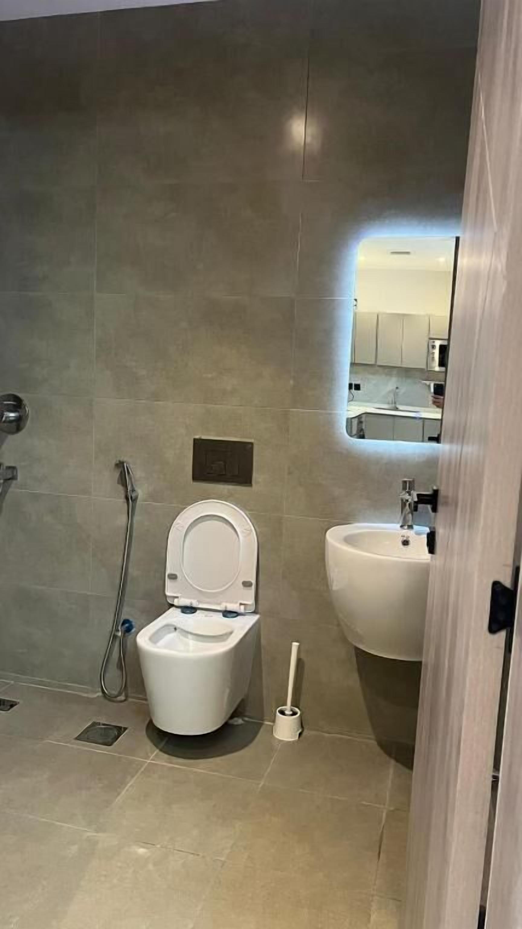 Een badkamer met toilet, hygiëneschuimer en wastafel.