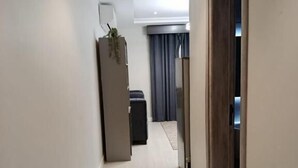Un pasillo con una puerta de madera, una planta y un mueble oscuro.