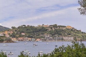 Eine Küstenstadt mit Häusern an einem Hügel, Booten im Wasser und blauem Himmel.