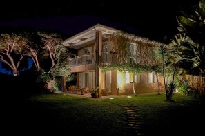 Ein zweistöckiges Haus mit Balkon, umgeben von üppigem Grün und einem gepflegten Rasen.